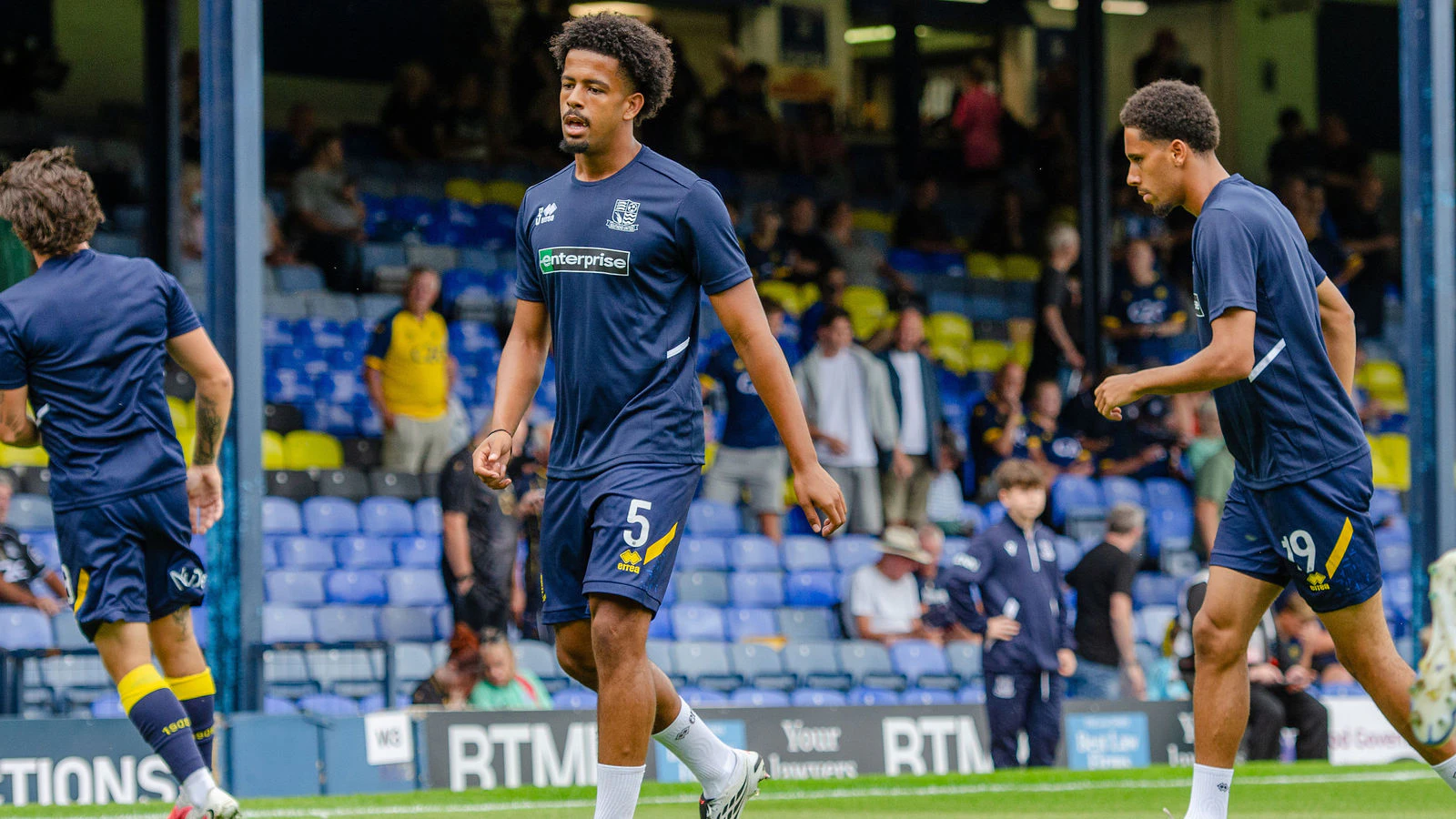 Three Southend United players warming up on the Roots Hall pitch.