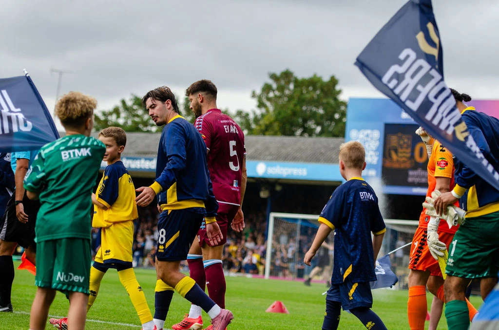 Southend and Scunthorpe players walk out with young mascots between flags.