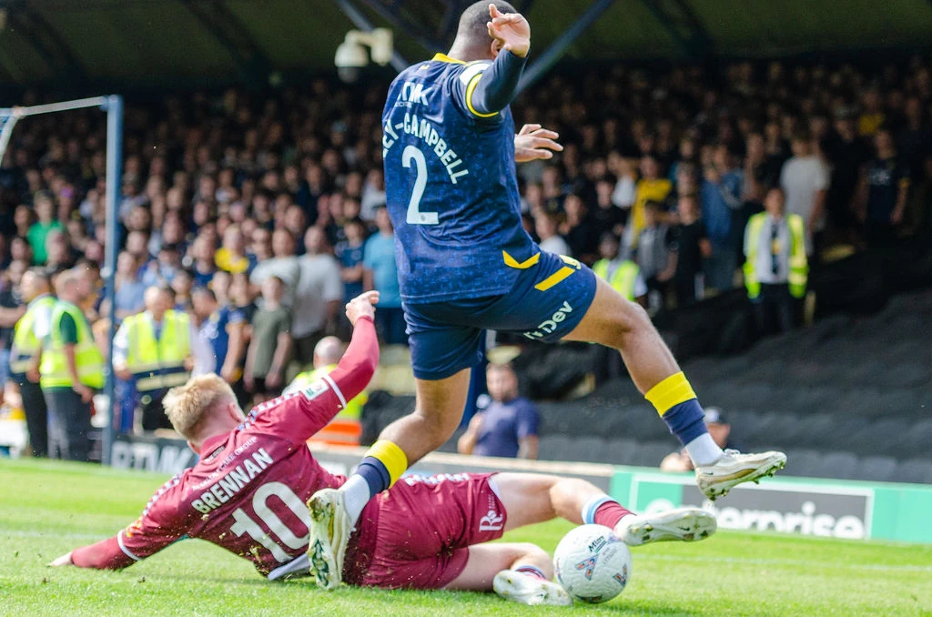Southend player leaps over a sliding Scunthorpe player as they contest the ball.