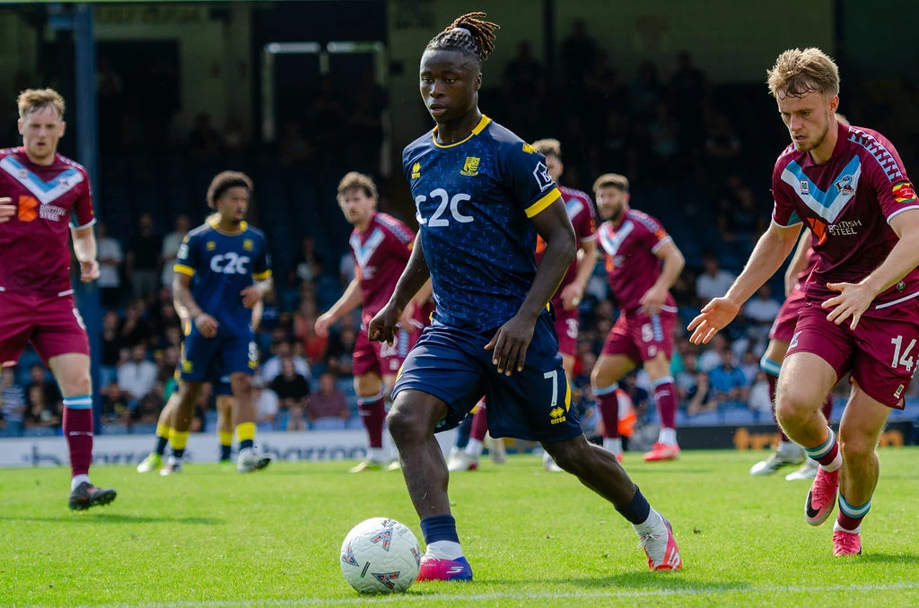 Southend attacker carries the ball forward as a Scunthorpe defender closes in.