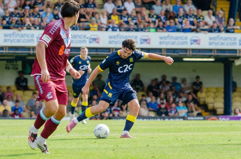 Southend player strikes the ball as a Scunthorpe defender closes in.