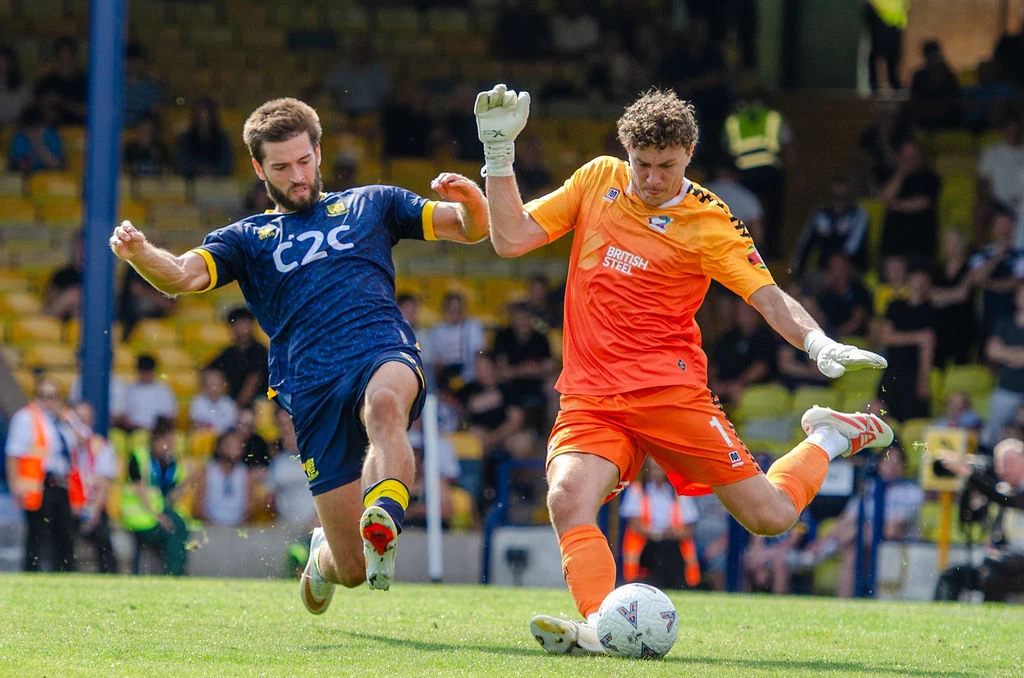 Southend player challenges as the Scunthorpe goalkeeper clears the ball.
