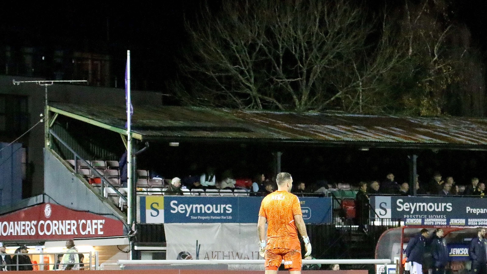 A Woking corner flag and goalkeeper in front of the Directors Stand at the Laithwaite Community Stadium.