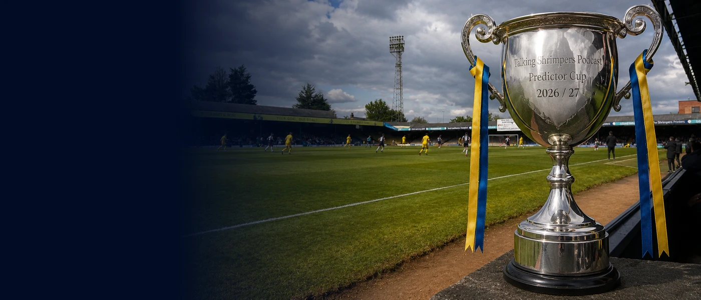 A silver prediction trophy with blue-and-yellow ribbons beside a football pitch